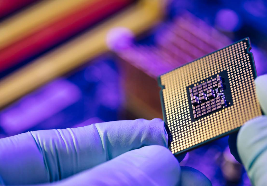 Gloved technician inspecting a microprocessor under inspection lighting